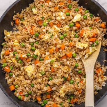 a wooden ladle in a pan of fried rice.